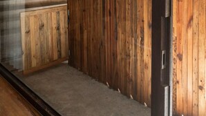 Een modern interieur met een betonnen trap, houten lambrisering en een glazen deur naar een buitenruimte.
