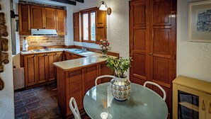 A kitchen with wooden cabinets, a glass table, and a vase with flowers.