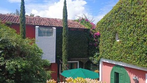 A courtyard with a tiled roof, a green door, and a wall covered in ivy.