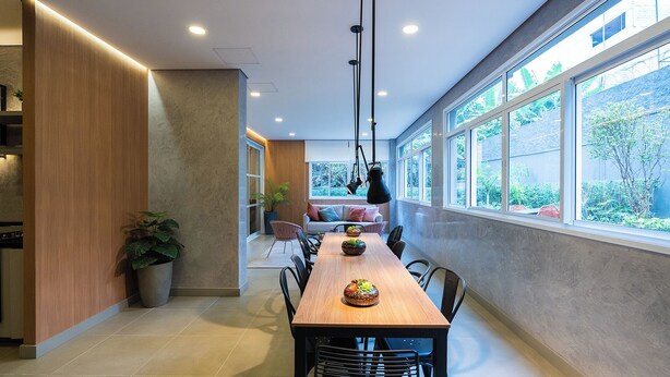 Un comedor moderno con una mesa de madera larga, sillas y una lámpara colgante.