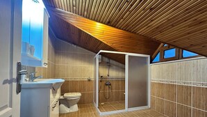 Moderni kylpyhuone, jossa on puinen katto, suihkukaappi ja wc.