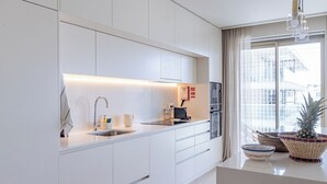 A modern kitchen with white cabinetry, a stainless steel sink, and a window with a view of buildings.