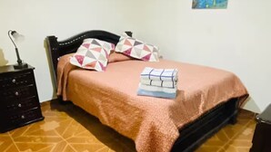 A bedroom with a bed, a dresser, a nightstand, and a painting on the wall.