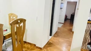 A hallway with a patterned floor leading to a room with a bed and a nightstand.