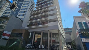 Il s'agit d'un bâtiment moderne à plusieurs étages, doté de grandes fenêtres et de balcons. Des panneaux indiquent la présence d'une entreprise et d'un espace de stationnement.