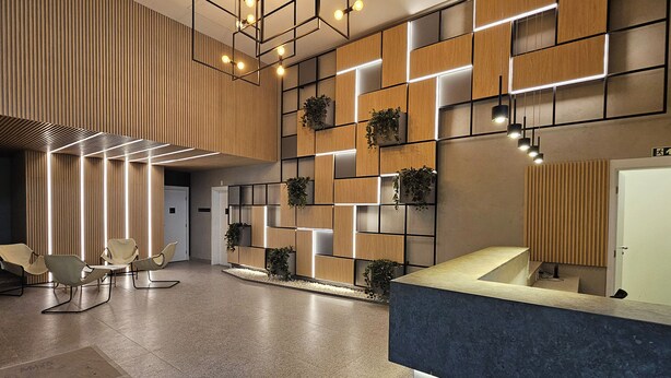 Un espace d’accueil moderne avec un mur revêtu de panneaux en bois, un comptoir d’accueil et un coin salon.