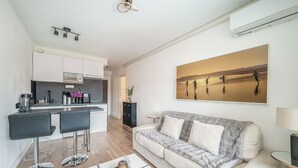 A modern living room with a sofa, a coffee table, and a kitchen area with a bar.