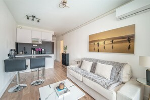 Ein modernes Wohnzimmer mit einer Couch, einem Couchtisch und einer Küchenzeile mit Bar.