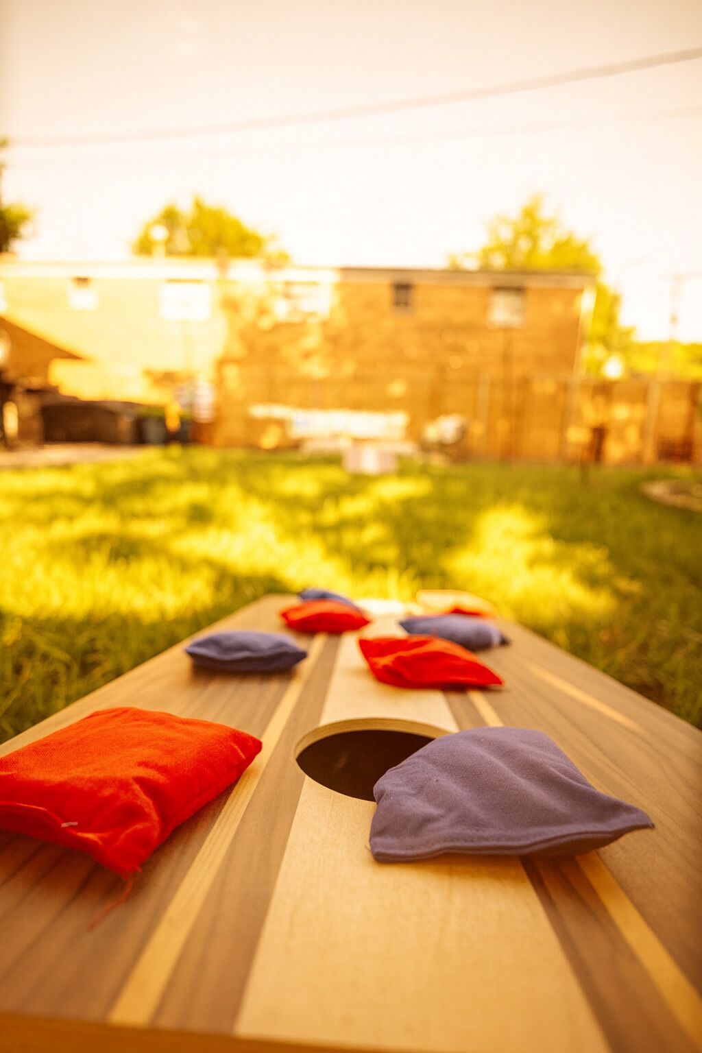 A wooden table with several colorful cushions in a grassy outdoor area.