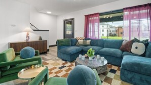 A modern living room with a sectional sofa, a round coffee table, and a lamp. - The Play Haus! Hot Tub, Game Room, Firepit, Families (Columbus)