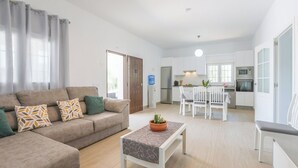 Een moderne woonkamer met een bank, een salontafel, en een eethoek met stoelen en een tafel.