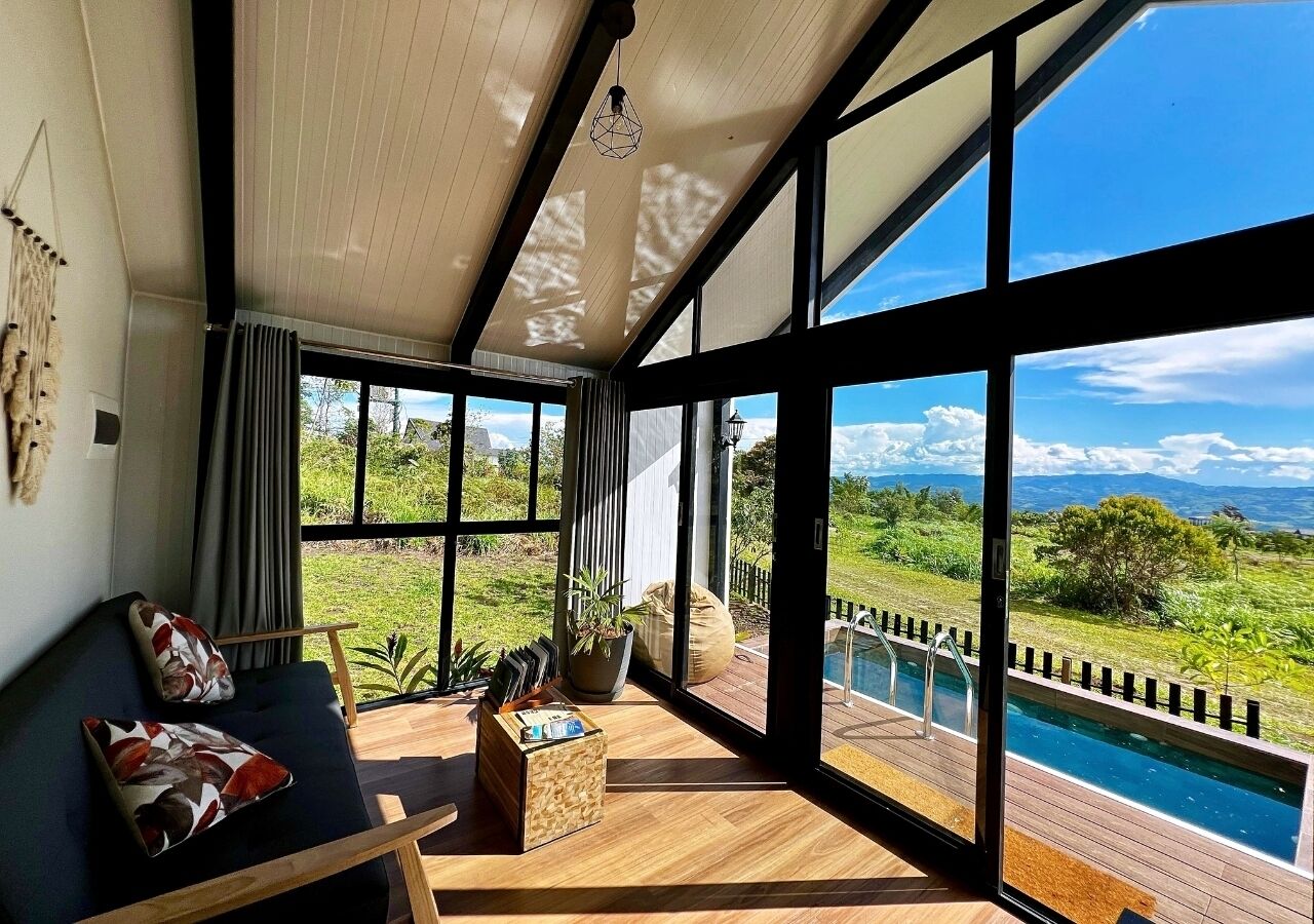 Sala de estar moderna com uma janela grande, piscina e vista para o exterior.
