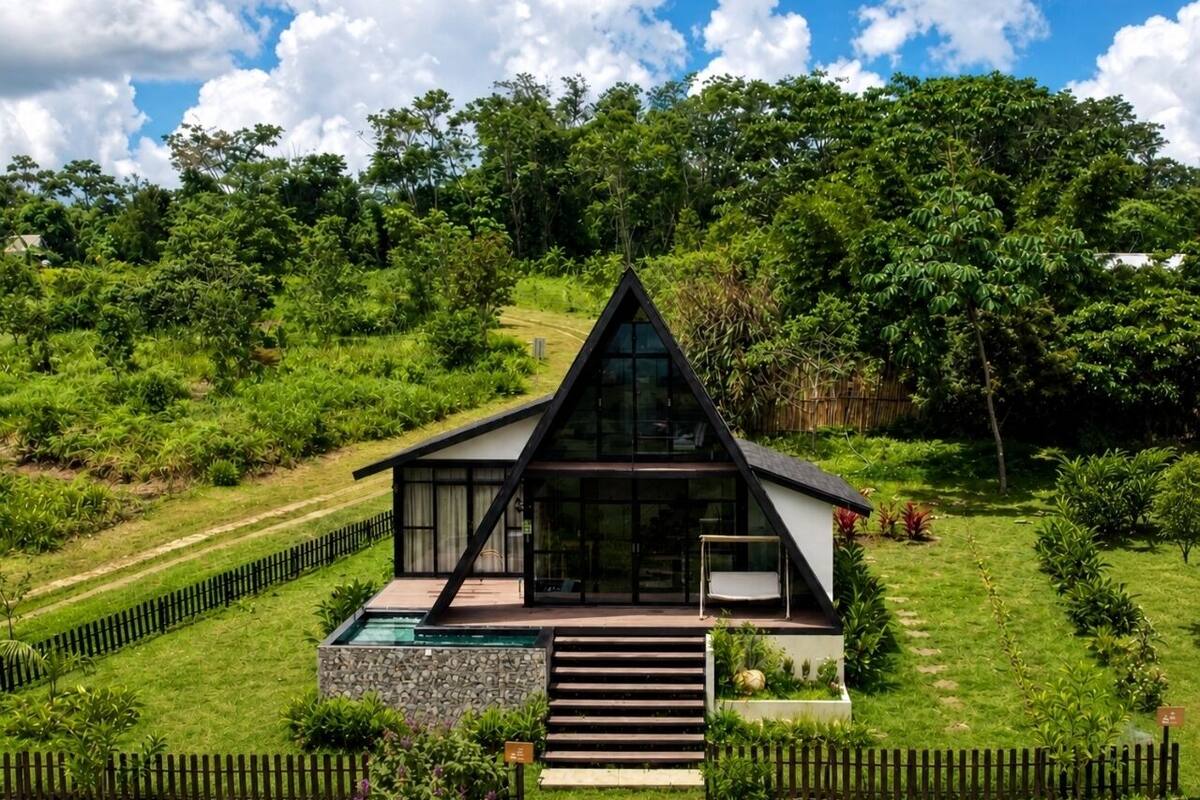Una casa moderna con techo triangular, piscina y jardín.