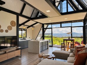 Una cocina moderna con una isla grande, un comedor con vistas y una sala de estar con sofá y mesa de centro.