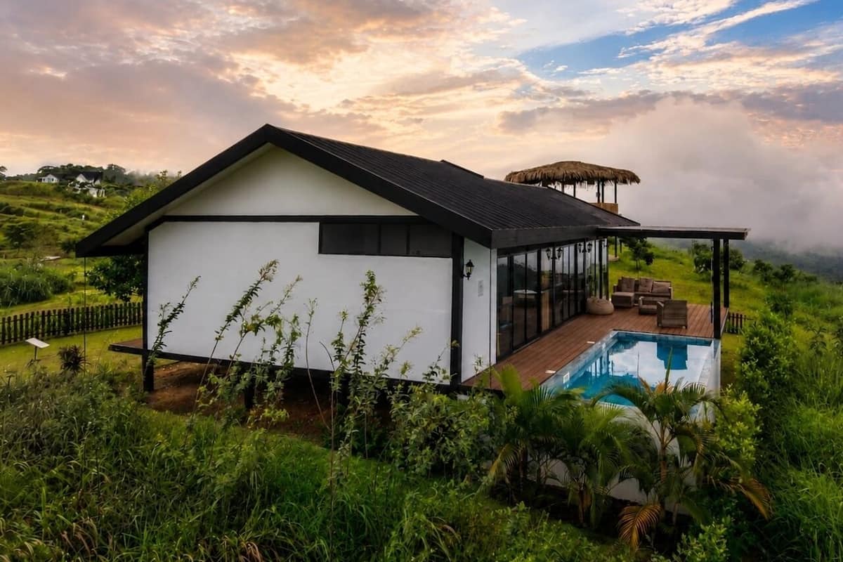 Una casa moderna con piscina, rodeada de exuberante vegetación.