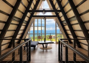 Amplia habitación con techo alto y ventanas grandes, con vistas al exterior.