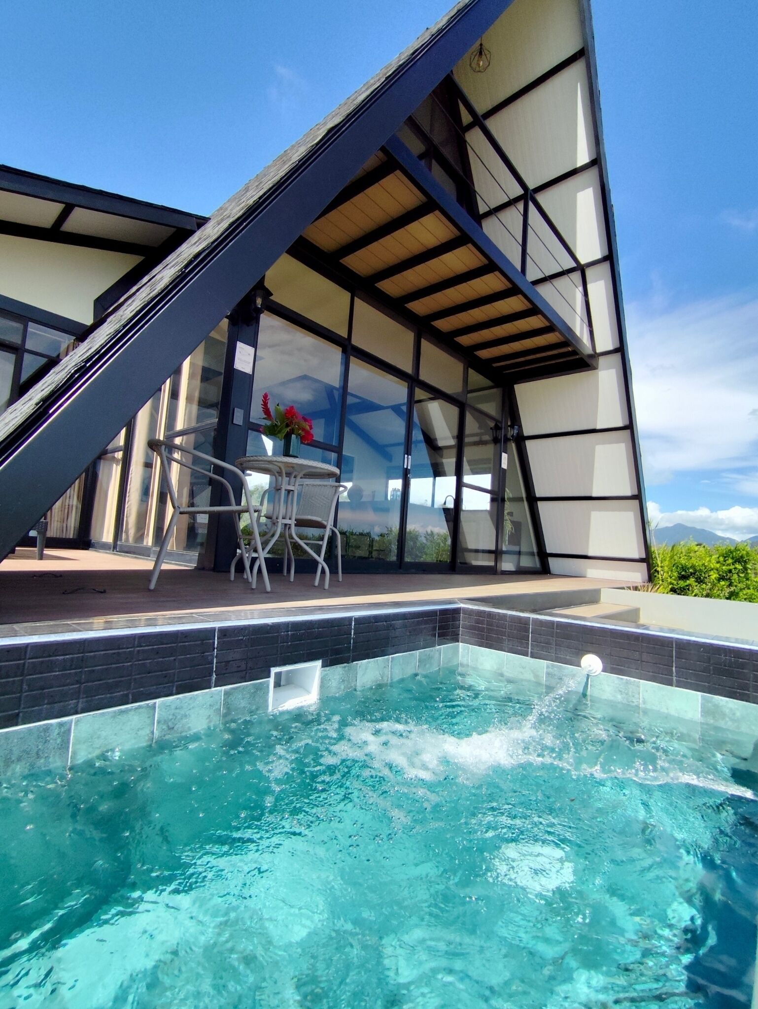 Un área de piscina moderna al aire libre, con vista despejada al cielo y montañas al fondo.