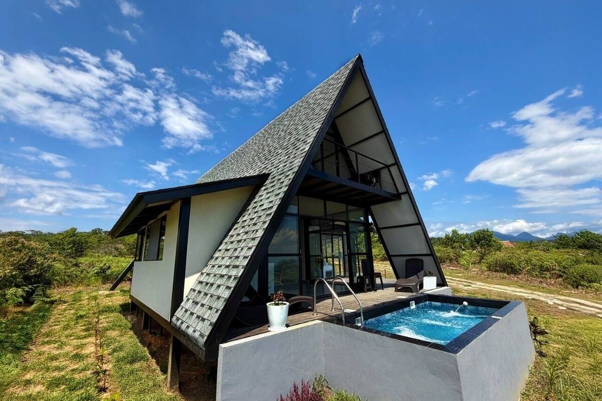 Una casa moderna con techo triangular, piscina y vistas del paisaje circundante.