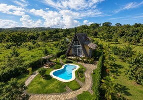 Una casa con piscina rodeada de exuberante vegetación y un sendero de piedra.