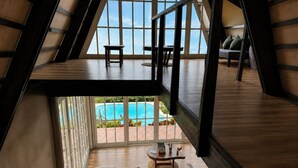 A high-ceilinged room with a view of a swimming pool, a sofa, and a coffee table. - El Resort de Yanashpa - Tarapoto (Cacatachi)