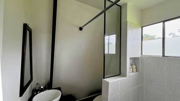 Une salle de bain moderne avec un lavabo blanc, un grand miroir et une fenêtre donnant sur l’extérieur.