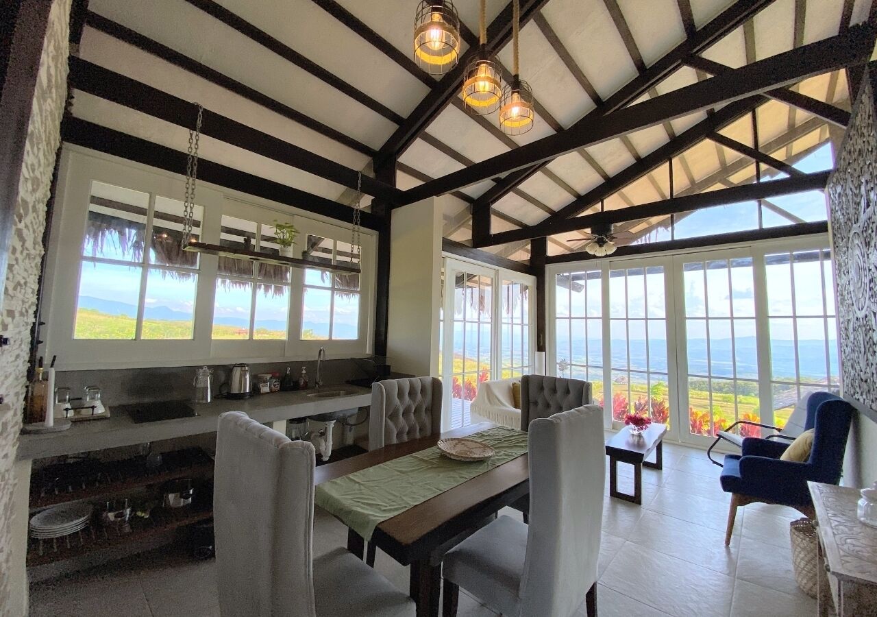 A spacious kitchen with a dining area, large windows, and a view of the landscape.