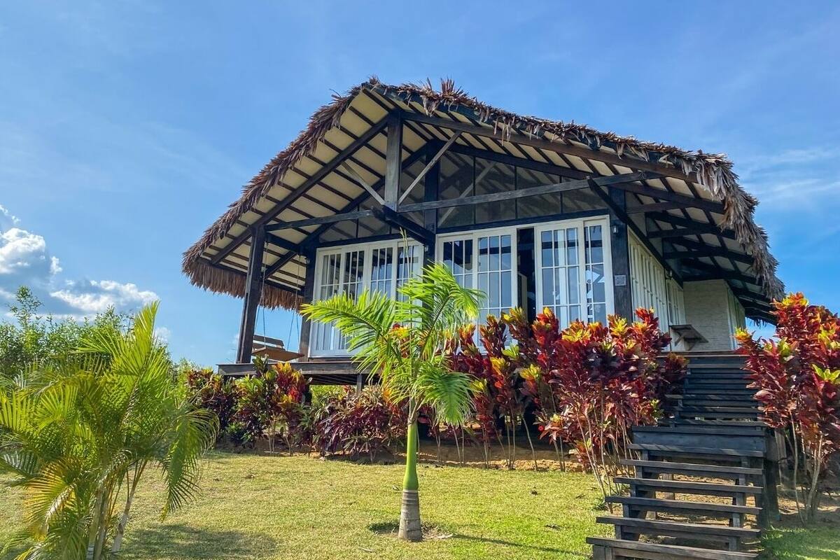Una casa con techo de paja y una escalera de madera que conduce a la entrada.