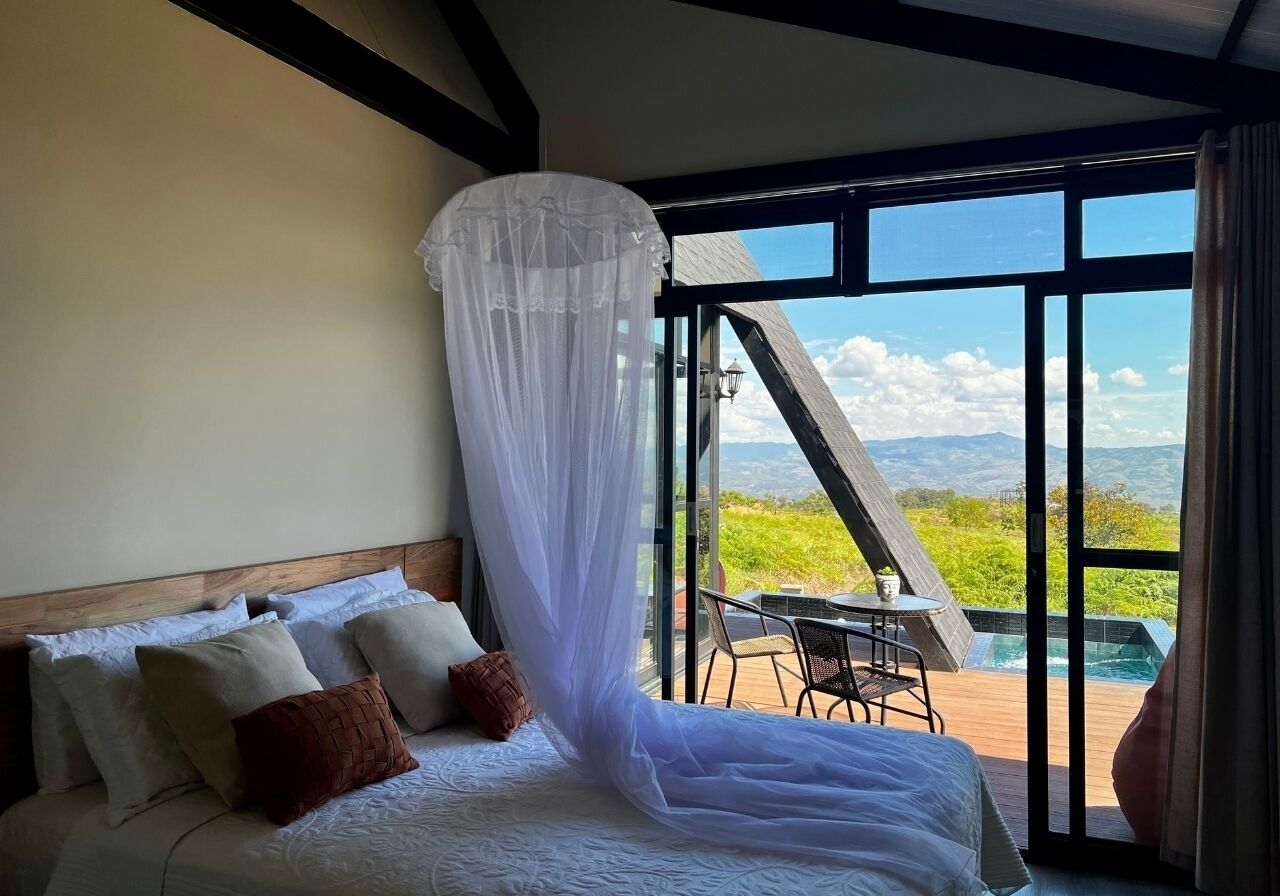 A bedroom with a large bed, a view of a hot tub, and a dining area.
