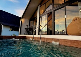 Un edificio moderno con piscina, ventanas amplias y mobiliario exterior.