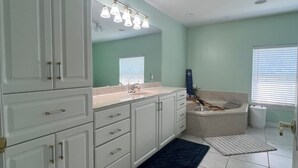 A bathroom with white cabinets, a sink, a bathtub, and a shower. There is a blue rug on the floor. - Family-Friendly Navarre Retreat w/Private Pool & Near the Beach (Navarre)