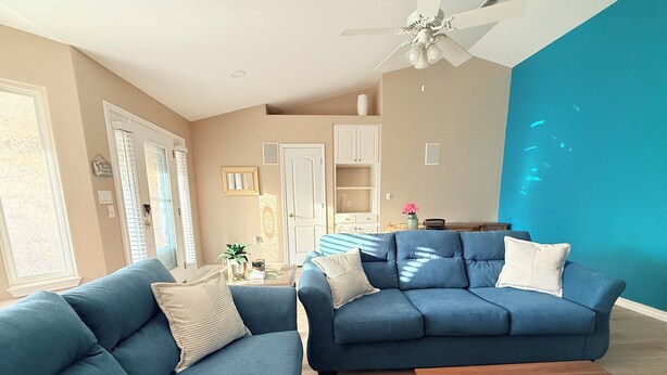 A living room with two blue sofas, a wooden coffee table, and a ceiling fan. - Family-Friendly Navarre Retreat w/Private Pool & Near the Beach (Navarre)