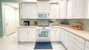 A kitchen with white cabinets, a microwave, a stove, and a blue rug. - Family-Friendly Navarre Retreat w/Private Pool & Near the Beach (Navarre)