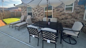 An outdoor patio with a table and chairs, a large umbrella, and a brick wall. - Family-Friendly Navarre Retreat w/Private Pool & Near the Beach (Navarre)