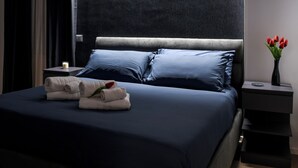 A neatly made bed with blue bedding, a vase with red flowers, and a small table with a candle. - CASA VACANZA BENVENUTO
2-bedroom,2-bathroom apartament in adorable Salerno (Salerno)