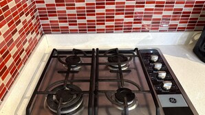 Una cucina con piano cottura a gas, quattro fuochi e un pannello di controllo con manopole e display digitale.