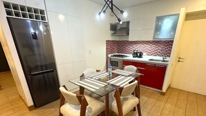 Una cucina moderna con frigorifero in acciaio inossidabile, un tavolo da pranzo con sedie, uno schienale piastrellato rosso e bianco e un forno a incasso.