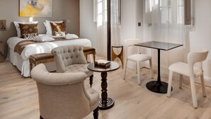Een hotelkamer met een bed, twee fauteuils, een klein rond tafeltje en een eettafel met stoelen.