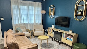 A living room with a sofa, chairs, a TV, and a bookshelf.