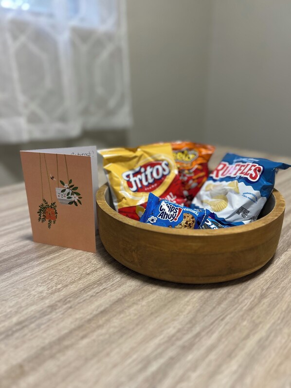 A wooden bowl filled with various snack chips on a wooden surface.