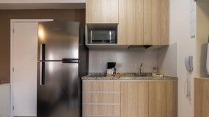 Une cuisine moderne équipée d’un réfrigérateur en acier inoxydable, d’un four à micro-ondes, de meubles en bois, d’un plan de travail en granit et d’une machine à café.