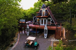 A two-story cabin with a balcony, a covered patio, and a small outdoor seating area.