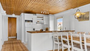 Een keuken met witte kasten, een houten aanrechtblad en een eethoek met witte stoelen en een houten tafel.