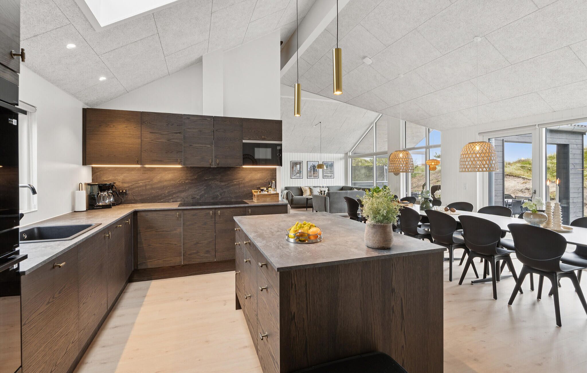 Una cocina moderna con armarios de madera oscura, una isla central e iluminación colgante.
