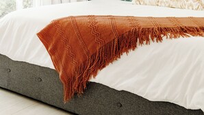 Une chambre à coucher moderne avec un grand lit, une table de chevet avec une lampe et une fenêtre avec des rideaux.