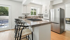 A modern kitchen with a central island, stainless steel appliances, and a seating area with bar stools. - Quiet & Updated Vancouver Getaway • Family & Pet Friendly. AC & WIFI (Vancouver)