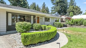 A modern single-story house with a well-maintained garden, a driveway, and a clear view of the surrounding trees. - Quiet & Updated Vancouver Getaway • Family & Pet Friendly. AC & WIFI (Vancouver)