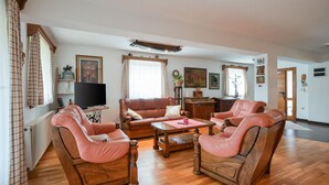 A living room with a wooden floor, leather armchairs, a wooden coffee table, and a television on a stand.