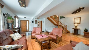 A spacious living room with leather sofas, a wooden coffee table, and a staircase leading to an upper floor.
