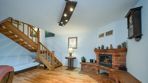 A room with a wooden staircase, a fireplace, and a bed.