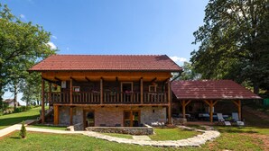 A two-story wooden house with a red-tiled roof, stone foundation, and a balcony with flower pots. - Amazing home in Veselici with sauna (Veselici)